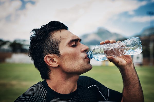 Mann drikker vann for å være hydrert